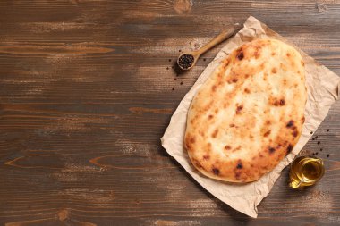 Lezzetli lavaş, bir sürahi yağ ve ahşap arka planda biber.