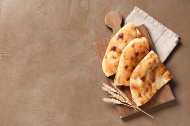 Lezzetli lavaş parçaları ve kahverengi grunge arka planında buğday dikenleri olan ahşap tahta tahta.