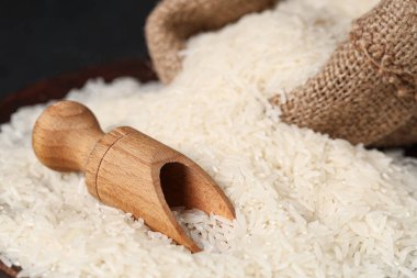 Dağınık çiğ pirinç ve ahşap kepçe, yakın plan.