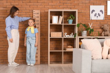 Anne, evdeki stadyumun yakınındaki kızının boyunu ölçüyor.