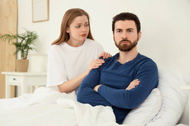 Yatak odasında kocasından özür dileyen genç bir kadın.