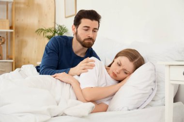Genç adam yatak odasında karısından özür diliyor.