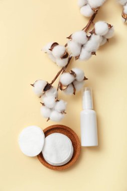 Renkli arka planda bir şişe kozmetik ürünü, ped ve pamuk dalı