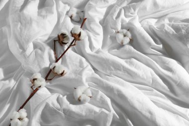 Pamuk filizi ve beyaz çarşaflarda çiçekler