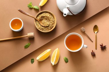 Bir fincan naneli karabuğday çayı, limon dilimleri ve kahverengi arka planda çaydanlık.