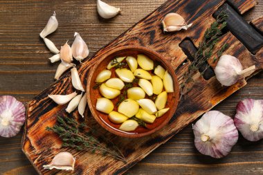 Tahta zemin üzerinde kekik olan bir kase taze sarımsak yağı.