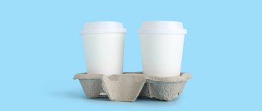 Açık mavi arka planda tutucusu olan paket kağıdı bardakları