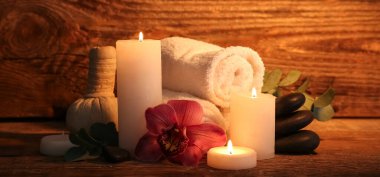 Ahşap zemin üzerinde yanan mumlar ve spa malzemeleri olan güzel bir kompozisyon.