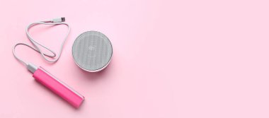 Güç bankası, USB kablosu ve pembe arkaplanda metin için boşluk olan hoparlör