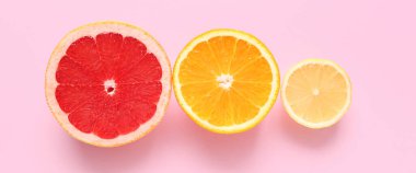 Pembe arka planda farklı turunçgillerden dilimler.