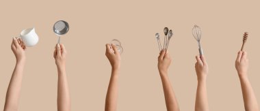 Bej arka planda pişirme aletleri olan kadın elleri