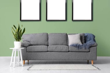 Oturma odasında gri kanepeli boş posterler.