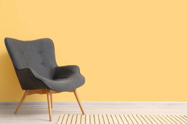 Modern grey armchair near yellow wall