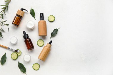 Hafif arkaplanda doğal kozmetik ürünleri, salatalık ve bitki yapraklarıyla kompozisyon