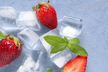 Mavi zemin üzerinde buz küpleri olan taze çilek.