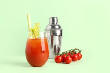 Yeşil arka planda kereviz ve sallanan bir bardak Bloody Mary.