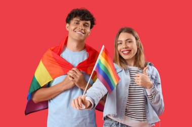 Kırmızı arka planda LGBT bayrakları olan genç bir çift