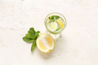 Beyaz arka planda salatalık ve nane aromalı bir bardak limonata.
