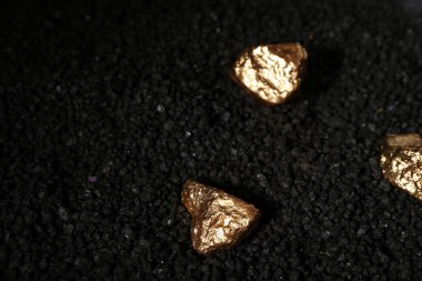 Siyah kömür üzerinde altın külçeler