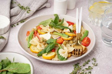 Beyaz arka planda bezelye ve fesleğenli lezzetli makarna salatası.