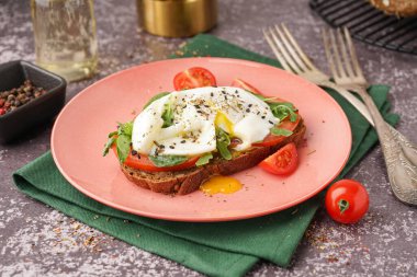 Gri zemin üzerinde yumurta olan lezzetli bir sandviç tabağı.