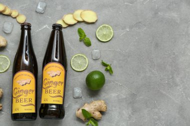 Gri zemin üzerinde taze zencefilli bira, nane, limon dilimleri ve buz küpleri olan kompozisyon