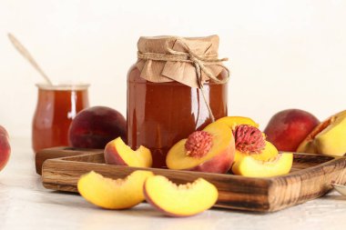 Tatlı şeftali reçelli kavanoz ve arka planda taze meyveler.