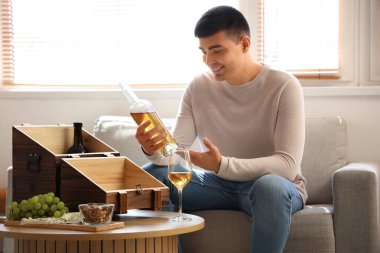 Young man with bottle of wine at home clipart