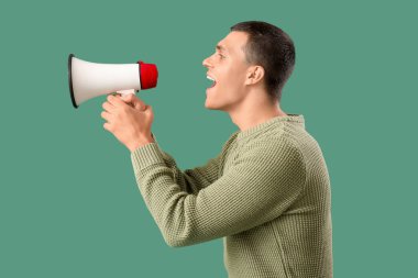 Yeşil arka planda megafona bağıran genç adam.