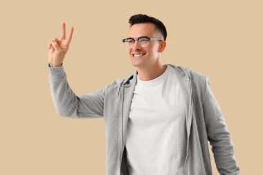 Genç adam bej arka planda zafer jesti yapıyor.