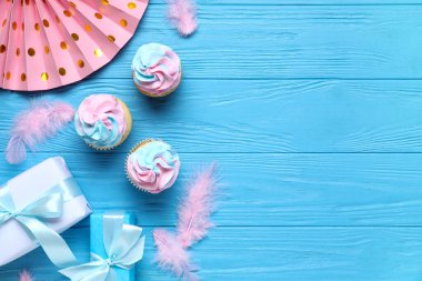 Hediye kutuları ve mavi ahşap arka planda süslemeleri olan lezzetli kekler. Cinsiyet ortaya çıkan parti kavramı