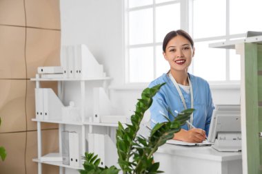 Klinikteki resepsiyonda çalışan Asyalı kadın stajyer.