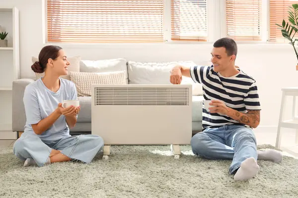 Evde kaloriferin yanında çay ısıtan genç bir çift.