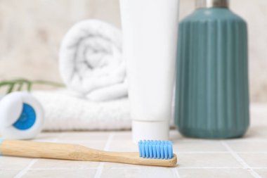 Bambu diş fırçası ve banyo malzemeleri açık fayans masasında, yakın plan.