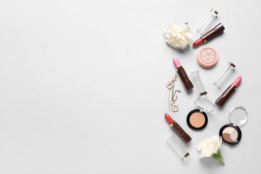 Beyaz arka planda küpeli ve çiçekli makyaj ürünleri