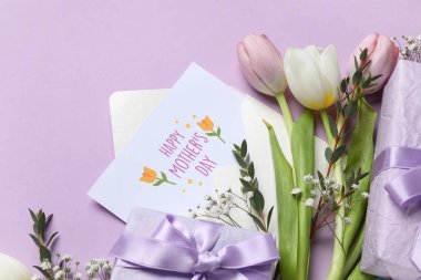 İçinde şenlikli kartpostal, çiçekler ve leylak arkaplanlı hediye kutuları olan bir zarf. Anneler Günü kutlaması