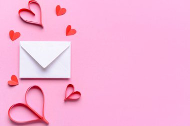 Üzerinde kağıt kalpler ve zarf olan kompozisyon pembe arka planda Sevgililer Günü kutlaması