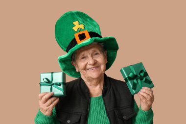Kahverengi arka planda hediye kutuları olan cüce şapkalı yaşlı kadın. Aziz Patrick Günü kutlaması