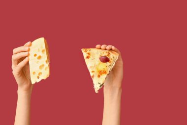 Kırmızı arka planda pizza dilimi ve peynir tutan kadın eller.
