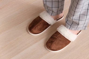 Erkek bacakları sıcak terlikler içinde lamine zeminde, yakın plan.