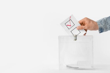 Beyaz arkaplana karşı oy sandığının yanındaki oy veren adam.