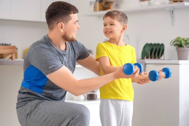 Young man and his little son training with dumbbells at home