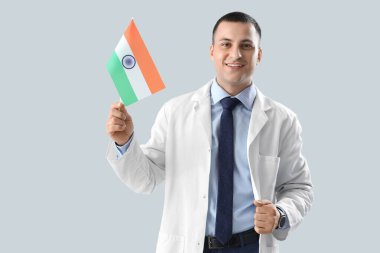 Gri arka planda Hindistan bayrağı olan erkek doktor. Ulusal Doktorların Günü kutlaması