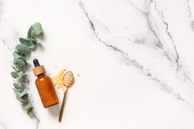 Deniz tuzu ve bir şişe okaliptüs içeren çay kaşığı mermer zemin üzerinde gerekli yağ