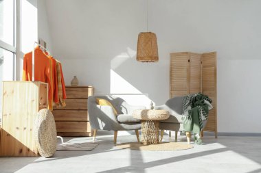 Sonbahar kıyafetleri ve koltuklarıyla aydınlık oturma odasının içinde.