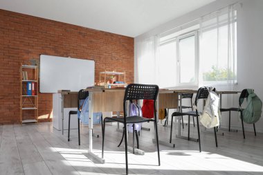 Beyaz tahtası, masası ve raf ünitesi olan boş sınıfın içi