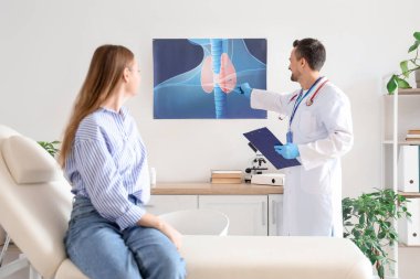 Erkek endokrinolog tiroit bezinin resmini klinikteki hastaya gösteriyor.