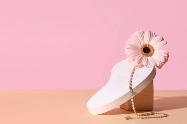 Süslü kolyeli dekoratif podyumlar ve renkli arka planda güzel Gerbera çiçekleri.