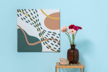 Üzerinde Gerbera çiçekleri olan vazo mavi duvardaki rafların yanında. Yakın çekim.