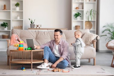 Babası evdeki dizüstü bilgisayarında çocuğuna bir şey gösteriyor.